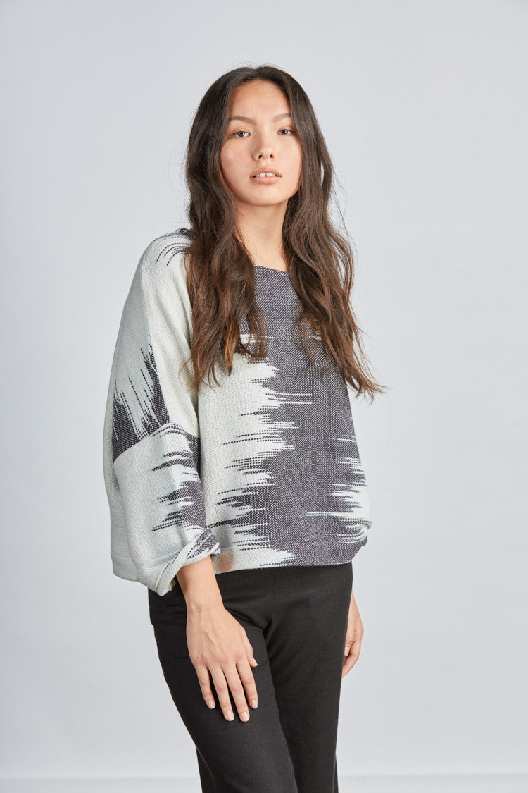 woman wearing a blue and white patterned hand woven oversized sweater with black pants