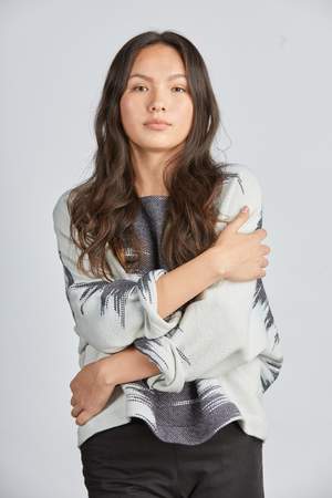 woman wearing a blue and white patterned hand woven oversized sweater with black pants