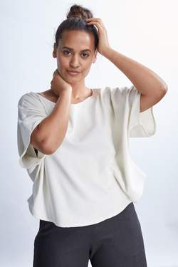 model wearing a white flowy raw silk noil blouse and black pants